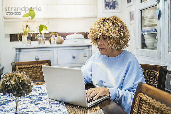 Reife Frau arbeitet am Laptop  während sie zu Hause sitzt