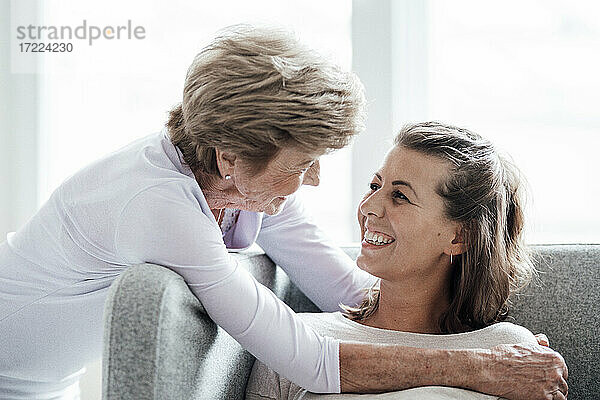 Fürsorgliche Großmutter schaut ihre Enkelin an  während sie sich auf dem Sofa umarmt
