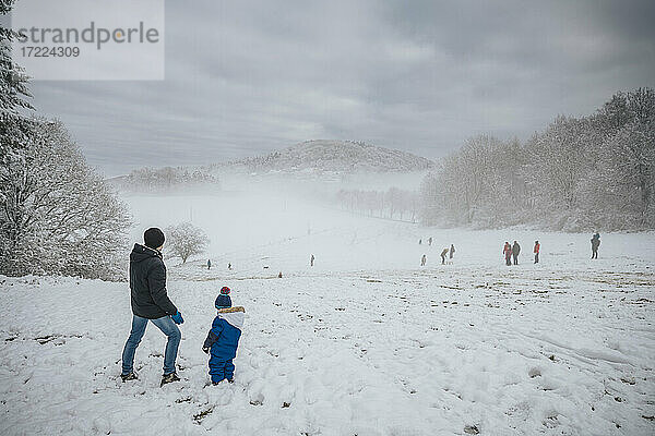 Vater und Sohn stehen im Schnee und betrachten die Landschaft im Winter