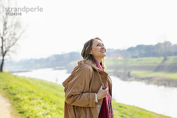 Fröhliche Frau  die am Flussufer steht und nach oben schaut