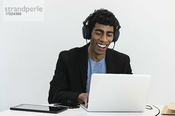 Gut gelaunter Geschäftsmann mit Headset bei einem Videogespräch über Laptop im Büro