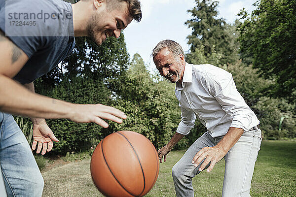 Verspielter Vater und Sohn mit Basketball im Hinterhof