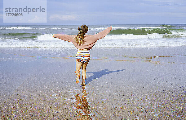 Teenager-Mädchen läuft am Strand Richtung Meer