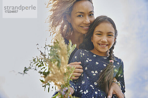 Lächelnde Mutter und Tochter mit einem Strauß Wildblumen
