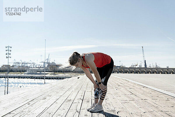 Junge Sportlerin ruht sich an einem sonnigen Tag auf dem Pier aus