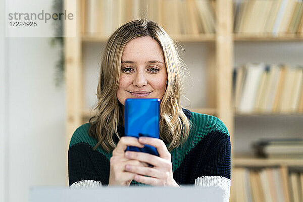 Lächelnde Frau nimmt Selfie durch Handy zu Hause