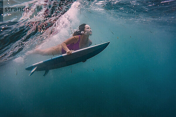 Frau surft auf Surfbrett unter Wasser