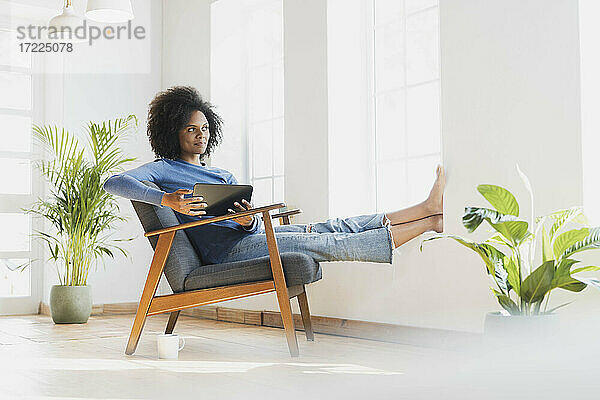 Nachdenkliche Frau mit digitalem Tablet  die zu Hause sitzt