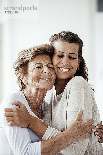 Lächelnde Frau und Enkelin umarmen sich zu Hause