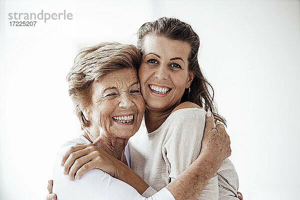 Fröhliche ältere Frau umarmt lächelnde Enkelin