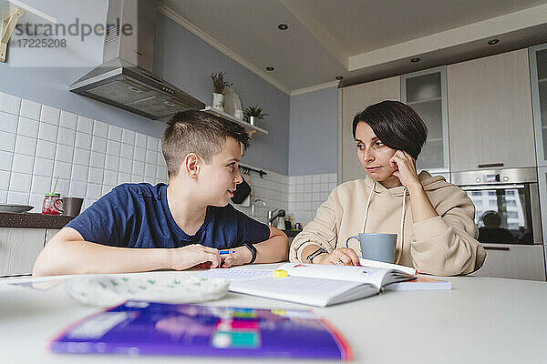 Mutter und Sohn schauen sich beim Lernen in der Küche zu Hause an