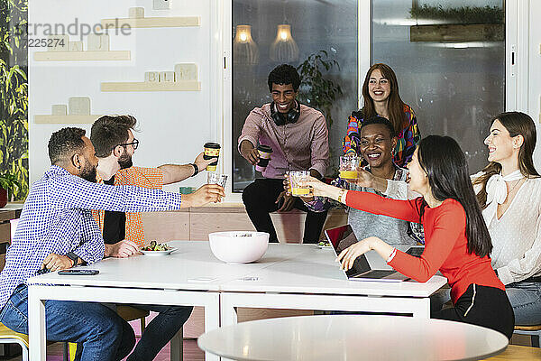 Geschäftsleute stoßen auf ein Getränk an  während sie in der Cafeteria im Büro sitzen