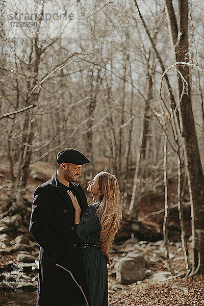Lächelndes Paar  das sich im Herbst im Wald stehend gegenseitig ansieht