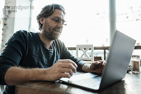 Mann benutzt Laptop in einem Kaffeehaus