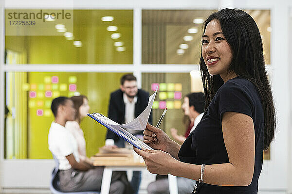 Junge Unternehmerin mit Dokument lächelnd im Büro