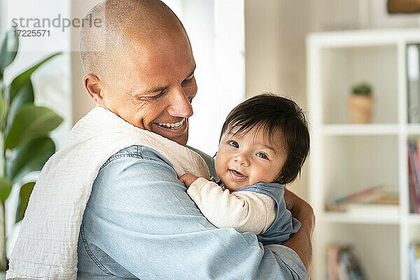 Glücklicher Vater betrachtet lächelnd süßes Baby zu Hause