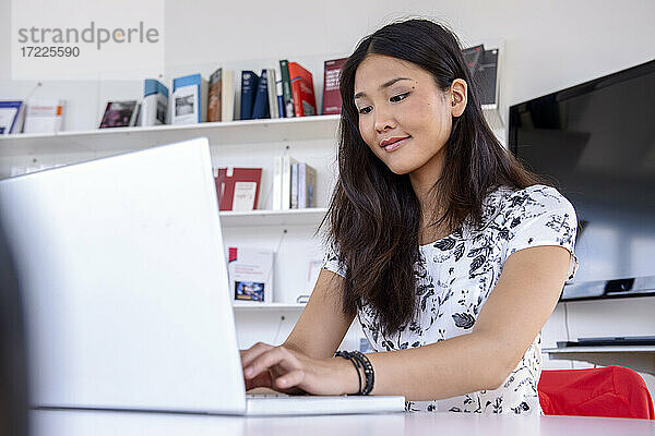Junge Frau arbeitet am Laptop in einer Bibliothek
