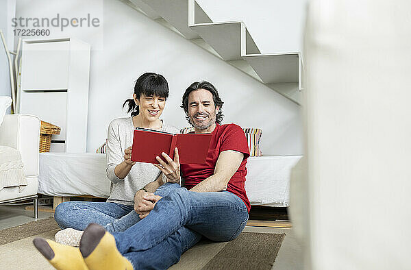 Älteres Paar betrachtet Fotoalbum  während es zu Hause sitzt