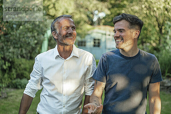 Lächelnder Sohn  der mit seinem wegschauenden Vater im Garten diskutiert