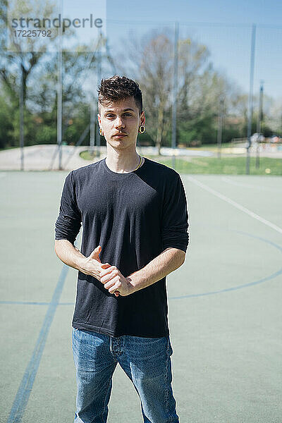 Junger Hipster-Mann  der an einem sonnigen Tag auf einem Sportplatz steht