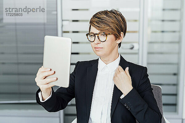 Geschäftsfrau mit kurzen braunen Haaren hält digitales Tablet im Büro