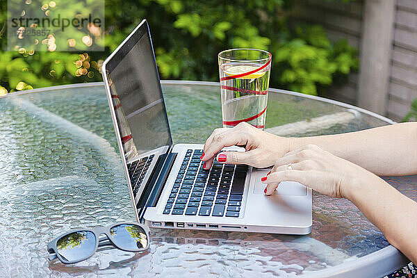 Frau arbeitet am Laptop  während sie an einem Tisch im Park sitzt