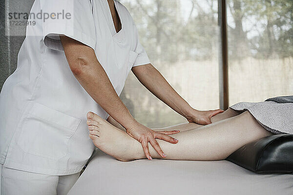 Therapeutin massiert das Bein eines Patienten im Krankenhaus