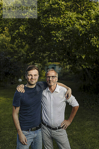 Sohn und Vater mit Arm um in Hinterhof stehend