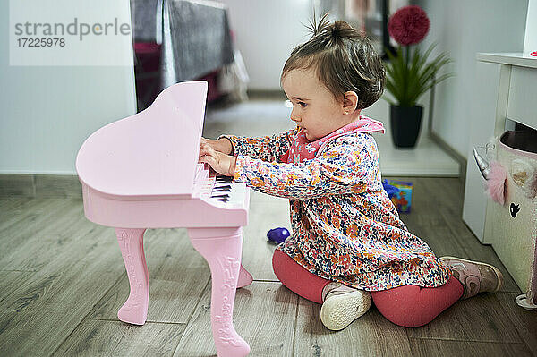 Baby spielt Klavier  während es zu Hause auf dem Boden sitzt