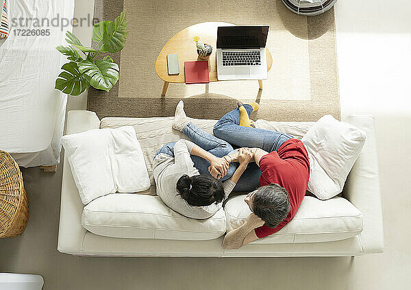 Zärtliches Paar  das sich umarmt  während es auf dem Sofa im Wohnzimmer sitzt
