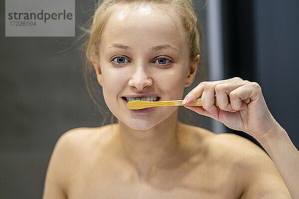 Junge Frau beim Zähneputzen mit Zahnbürste im Badezimmer