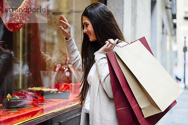 Schöne lächelnde Frau hält Taschen beim Schaufensterbummel