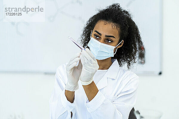 Eine Forscherin untersucht ein Reagenzglas im Labor während einer Pandemie