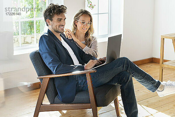 Lächelndes Paar schaut zu Hause auf den Laptop