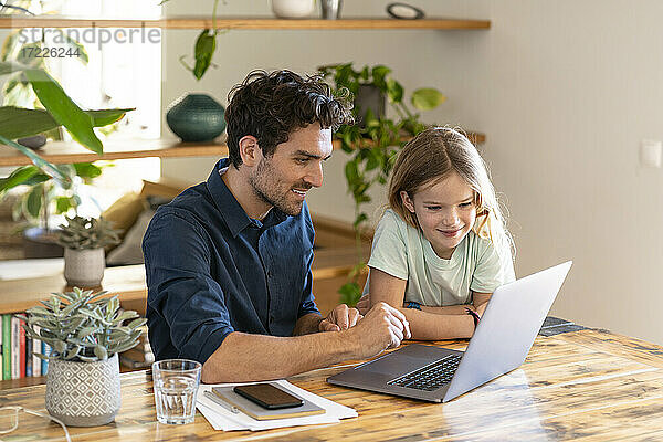 Glücklicher Vater und Tochter mit Blick auf den Laptop