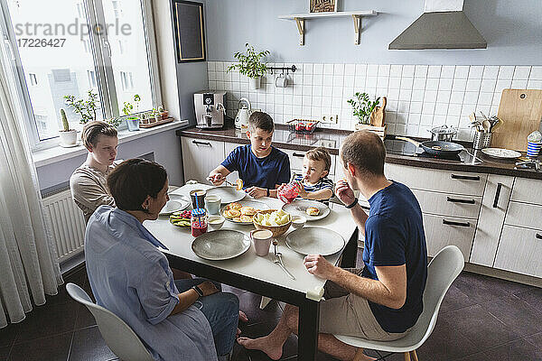 Glückliche Familie beim Essen am Esstisch in der Küche zu Hause