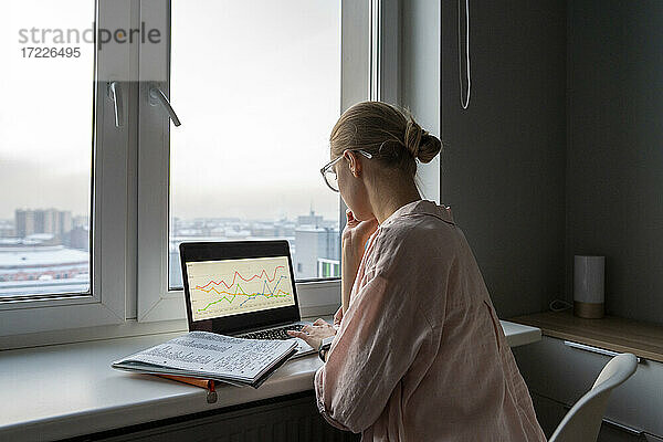 Frau arbeitet am Laptop  während sie zu Hause im Büro sitzt