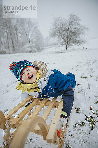 Fröhlicher Junge beim Schlittenfahren im Schnee