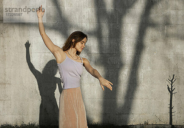 Frau mit erhobenen Armen tanzt gegen die Wand