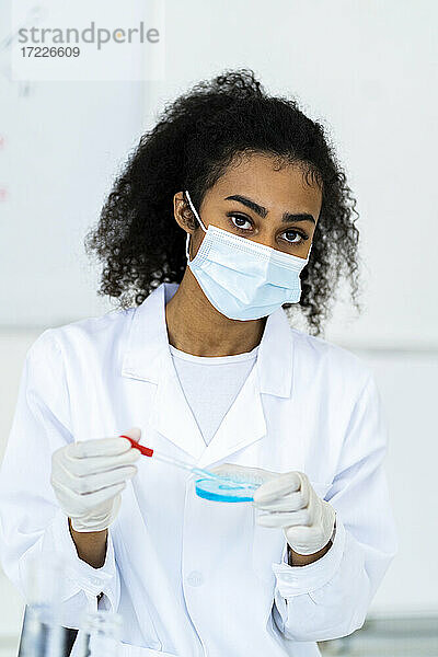 Forscherin mit Gesichtsschutzmaske bei der Arbeit im Labor
