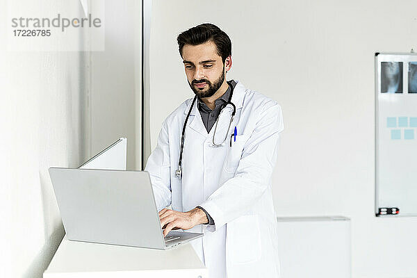 Gut aussehender männlicher Arzt mit Laptop im Krankenhaus