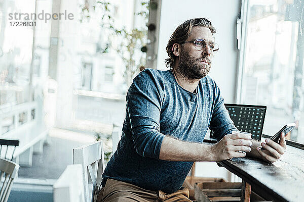 Mann mit Kaffeetasse am Laptop in einem Café sitzend