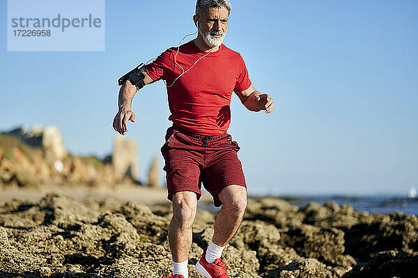 Mann läuft durch Felsen am Strand an einem sonnigen Tag