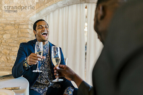 Eleganter Mann lachend und mit Champagner in der Hand beim Bankett