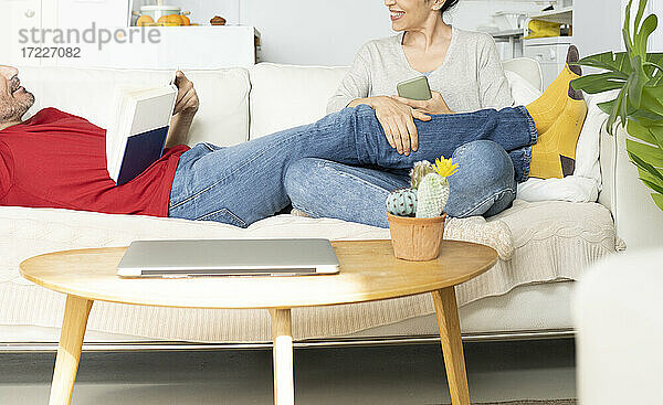 Ein Paar diskutiert miteinander  während es sich auf dem Sofa zu Hause entspannt