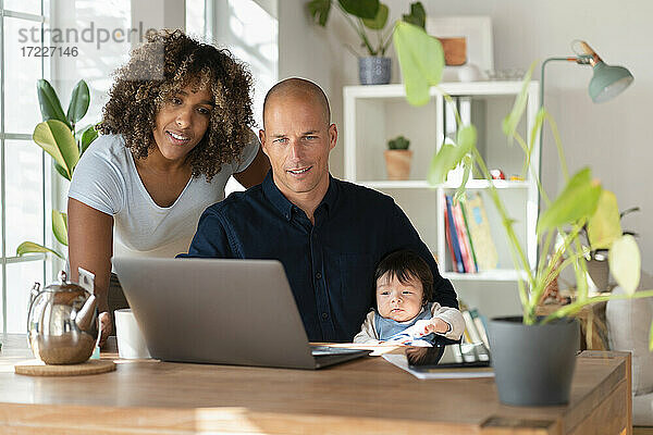 Mutter  Vater und Tochter schauen zu Hause auf den Laptop