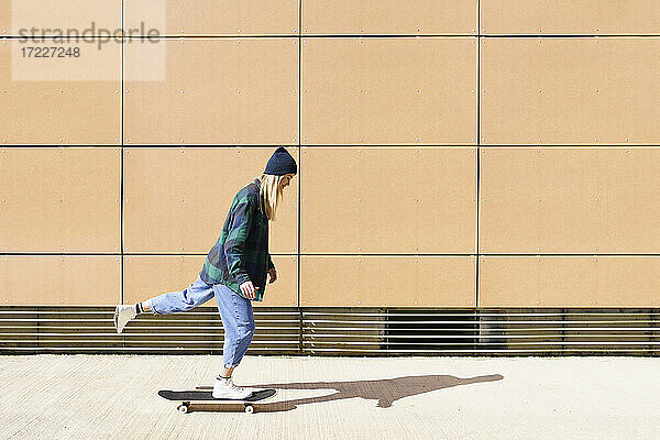 Junge Frau beim Skateboarden an einem sonnigen Tag