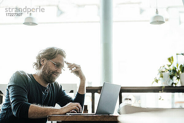 Männlicher Unternehmer mit Laptop in einem Cafe