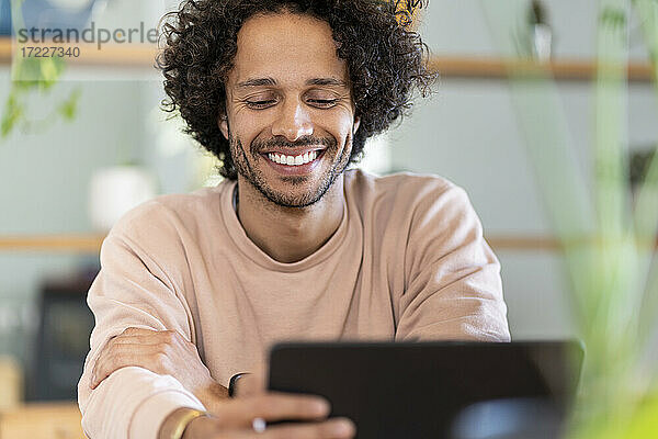 Gut gelaunter männlicher Unternehmer  der zu Hause ein digitales Tablet benutzt