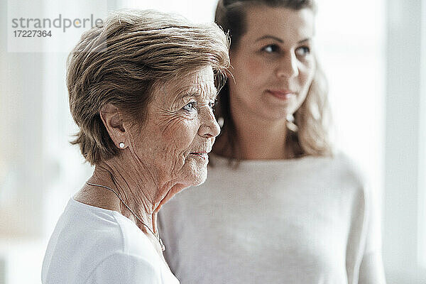 Ältere Frau schaut weg  während sie bei ihrer Enkelin zu Hause steht